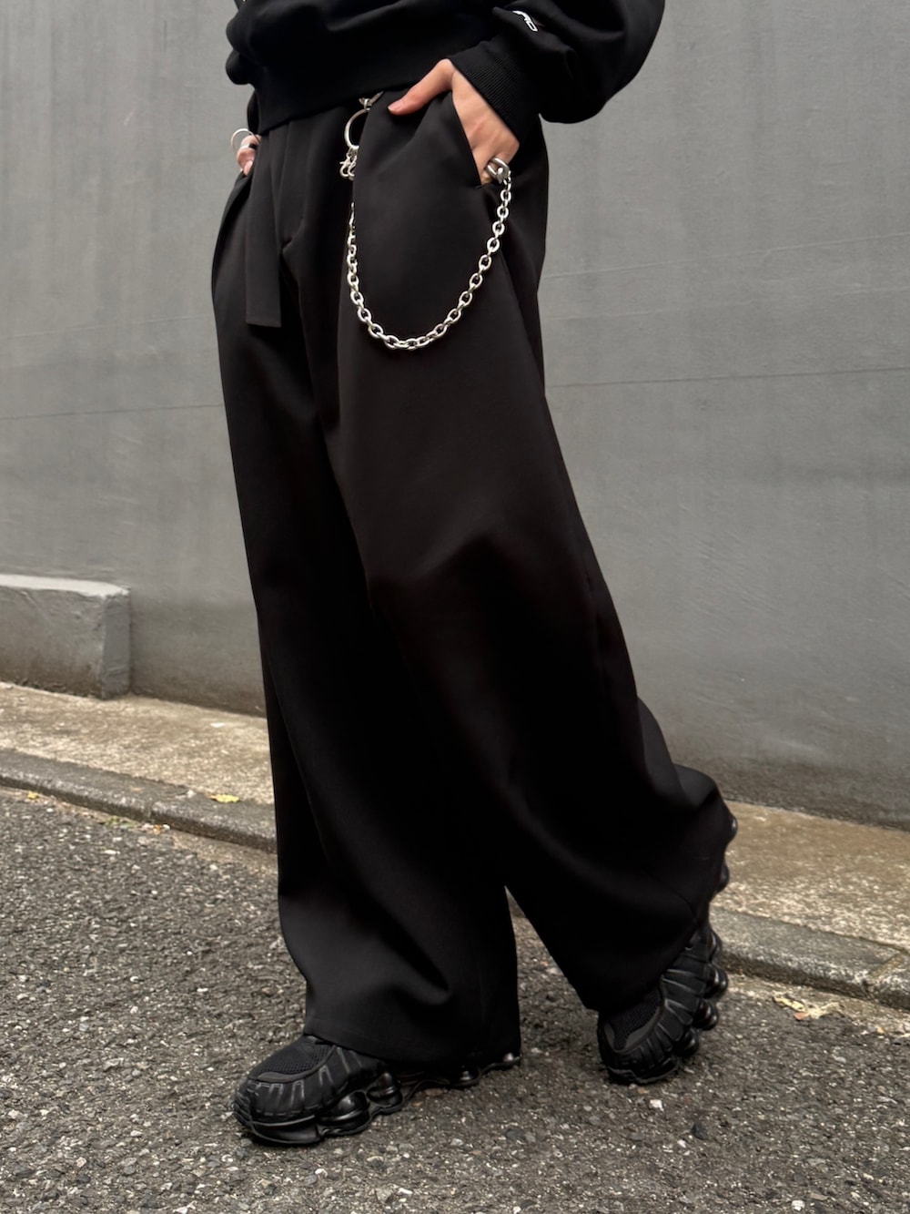 ブラック系のスウェット、ブラック系のスラックス、シルバー系のウォレットチェーンを着用したメンズの春コーディネートの8枚目の写真