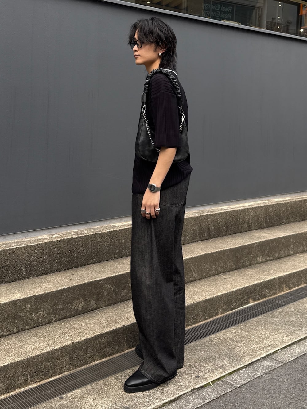 ブラック系のニット/セーター、ブラック系のショルダーバッグ、ブラック系のデニムパンツを着用したメンズの春コーディネートの2枚目の写真