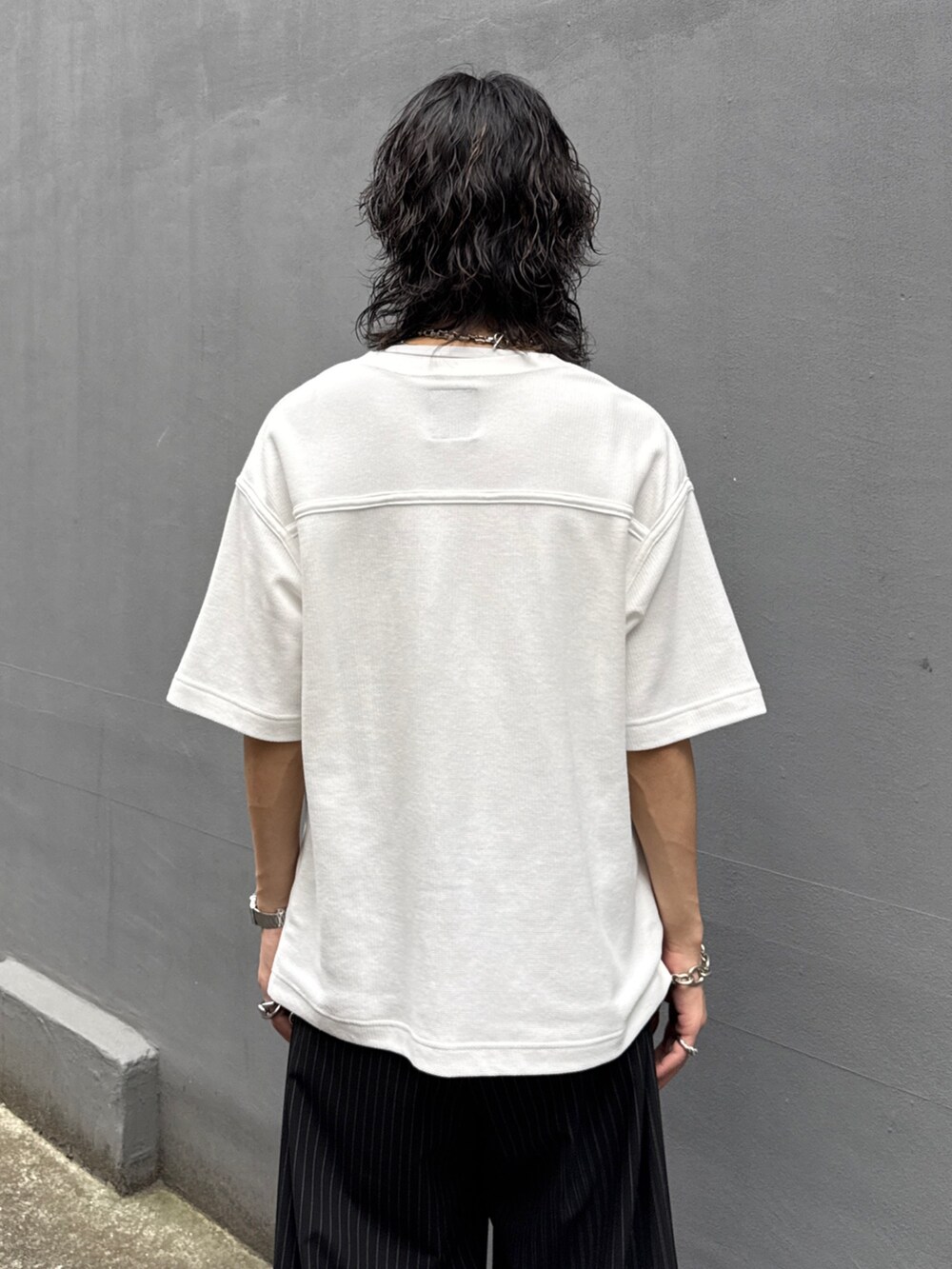 ホワイト系のTシャツ/カットソー、ブラック系のスラックス、シルバー系のウォレットチェーンを着用したメンズの夏コーディネートの6枚目の写真