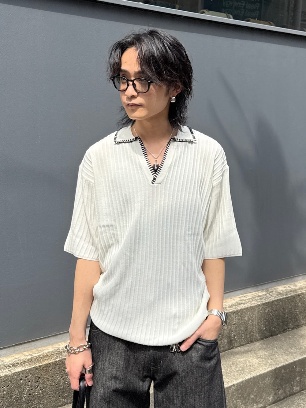 ブラック系のデニムパンツ、ブラック系のショルダーバッグ、ホワイト系のニット/セーターを着用したメンズの春コーディネートの4枚目の写真