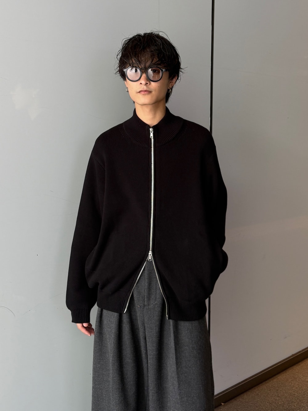 ブラック系のニット/セーター、グレー系のスラックスを着用したメンズの秋コーディネートの4枚目の写真
