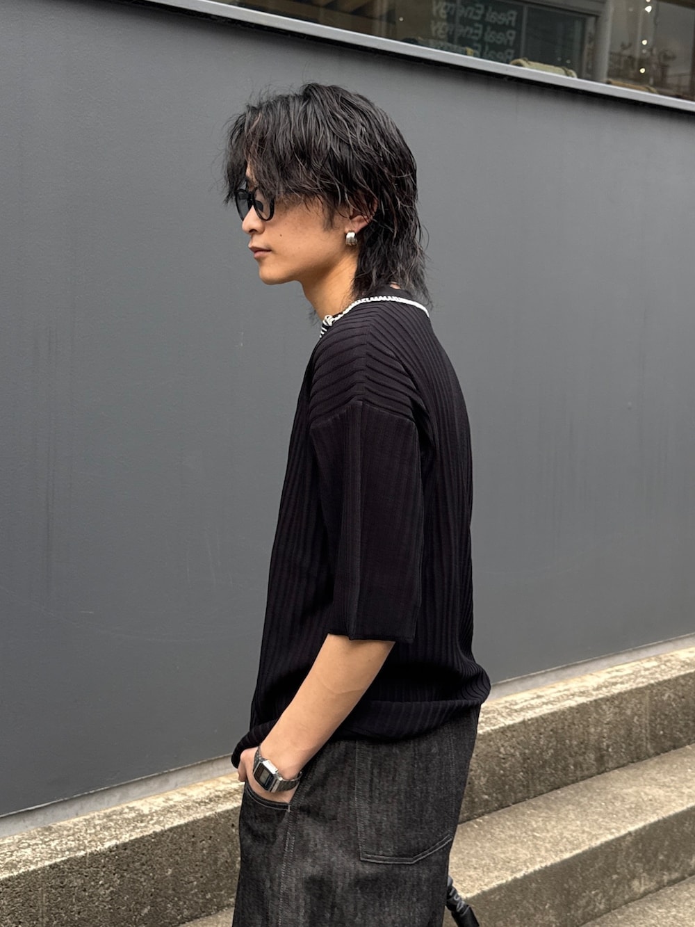 ブラック系のニット/セーター、ブラック系のショルダーバッグ、ブラック系のデニムパンツを着用したメンズの春コーディネートの5枚目の写真