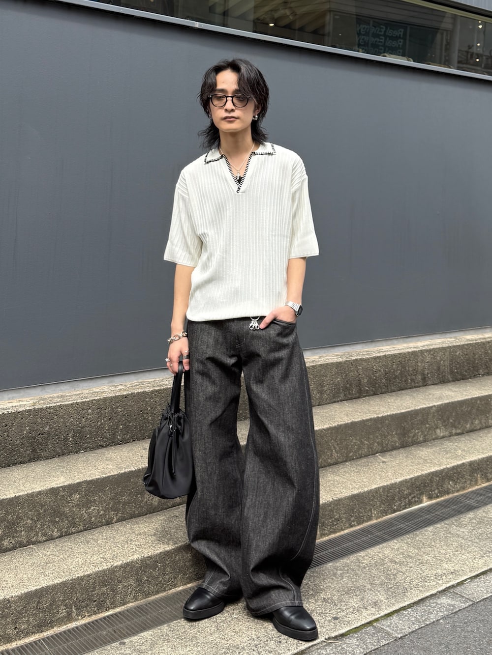 ブラック系のデニムパンツ、ブラック系のショルダーバッグ、ホワイト系のニット/セーターを着用したメンズの春コーディネートの7枚目の写真