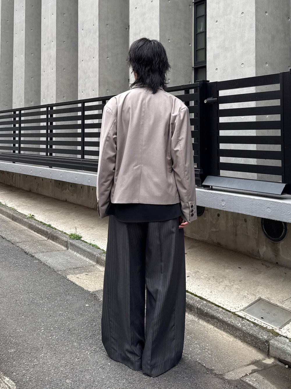 グレー系のスラックス、グレー系のテーラードジャケット、ブラック系のシャツ/ブラウスを着用したメンズの春コーディネートの2枚目の写真