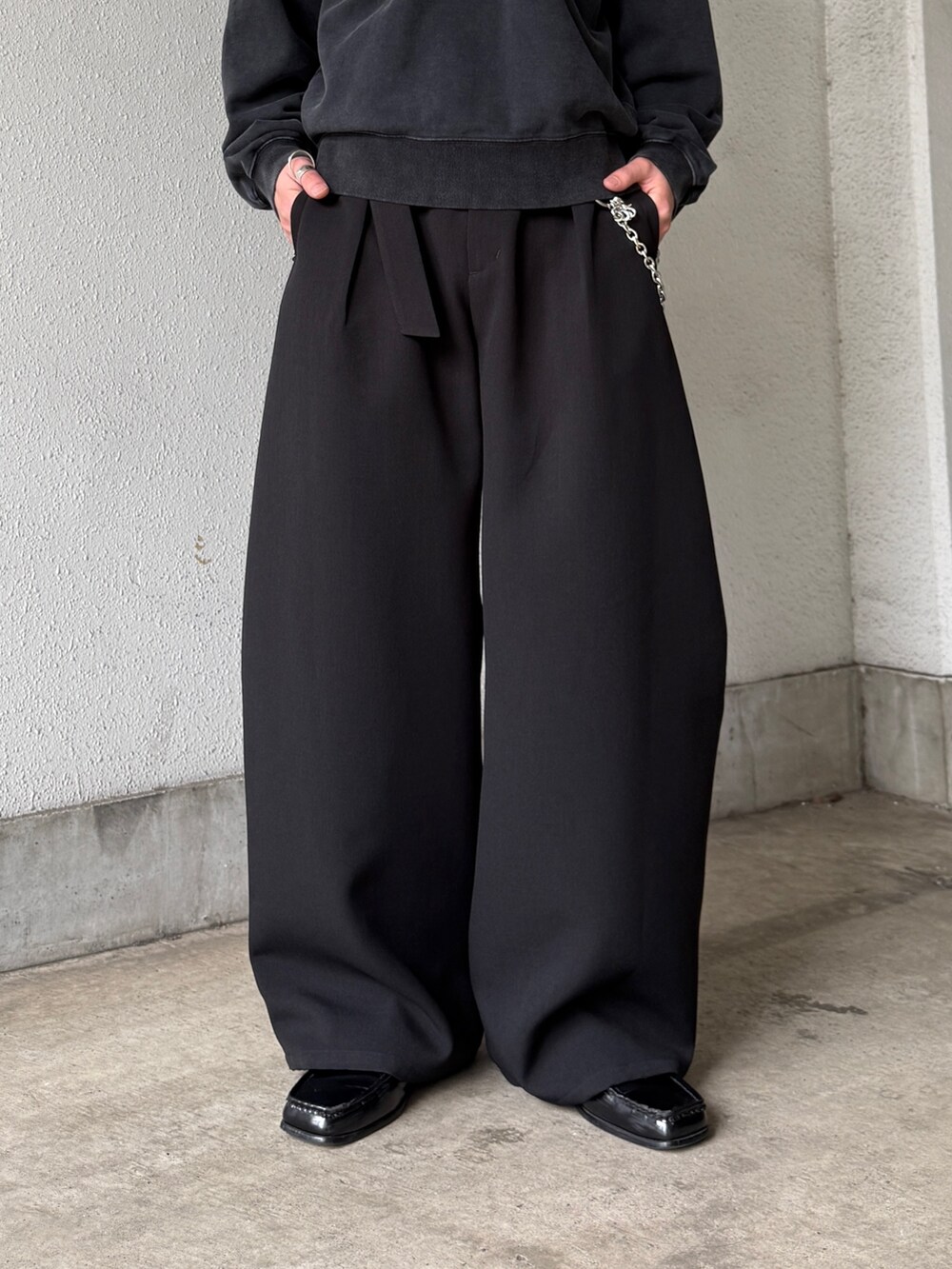 ブラック系のスウェット、ブラック系のスラックス、シルバー系のネックレスを着用したメンズの春コーディネートの7枚目の写真