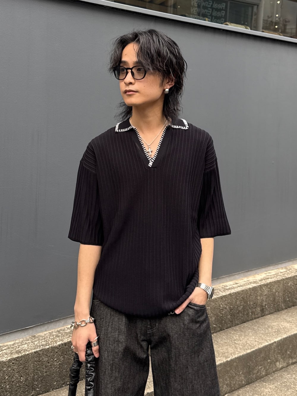 ブラック系のニット/セーター、ブラック系のショルダーバッグ、ブラック系のデニムパンツを着用したメンズの春コーディネートの4枚目の写真