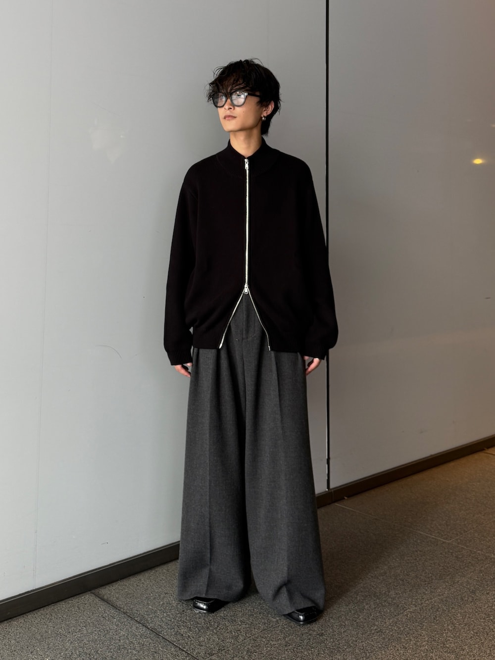ブラック系のニット/セーター、グレー系のスラックスを着用したメンズの秋コーディネートの2枚目の写真