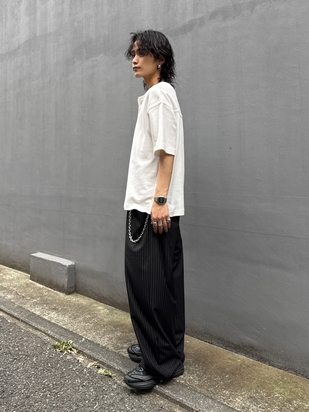 ホワイト系のTシャツ/カットソー、ブラック系のスラックス、シルバー系のウォレットチェーンを着用したメンズの夏コーディネートの2枚目の写真