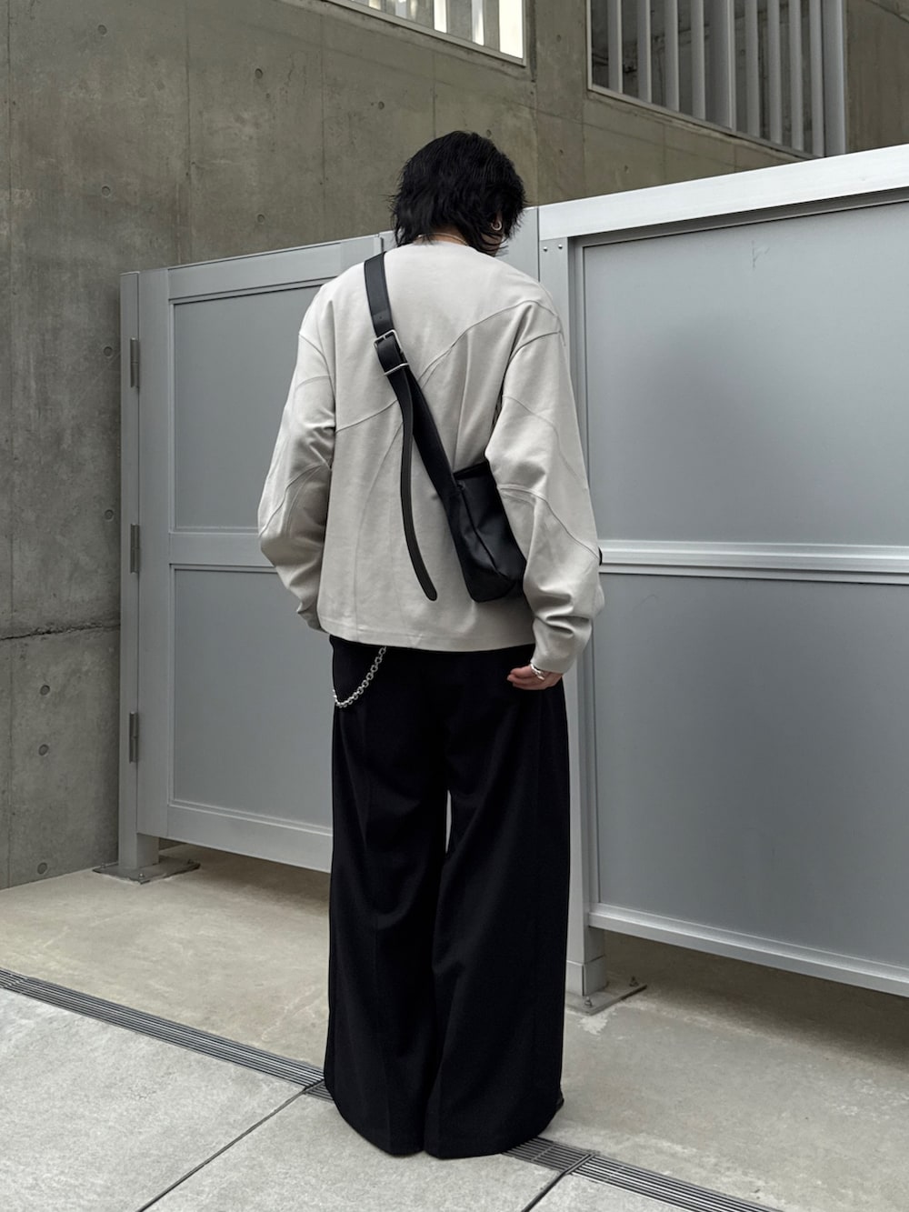 グレー系のTシャツ/カットソー、ブラック系のショルダーバッグ、ブラック系のスラックスを着用したメンズの春コーディネートの2枚目の写真
