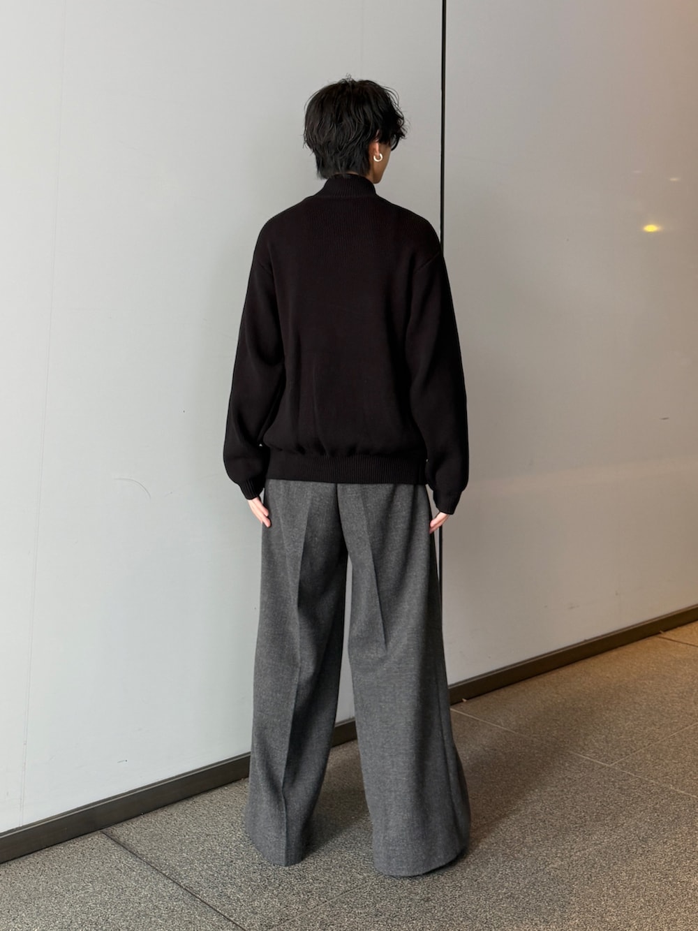 ブラック系のニット/セーター、グレー系のスラックスを着用したメンズの秋コーディネートの3枚目の写真
