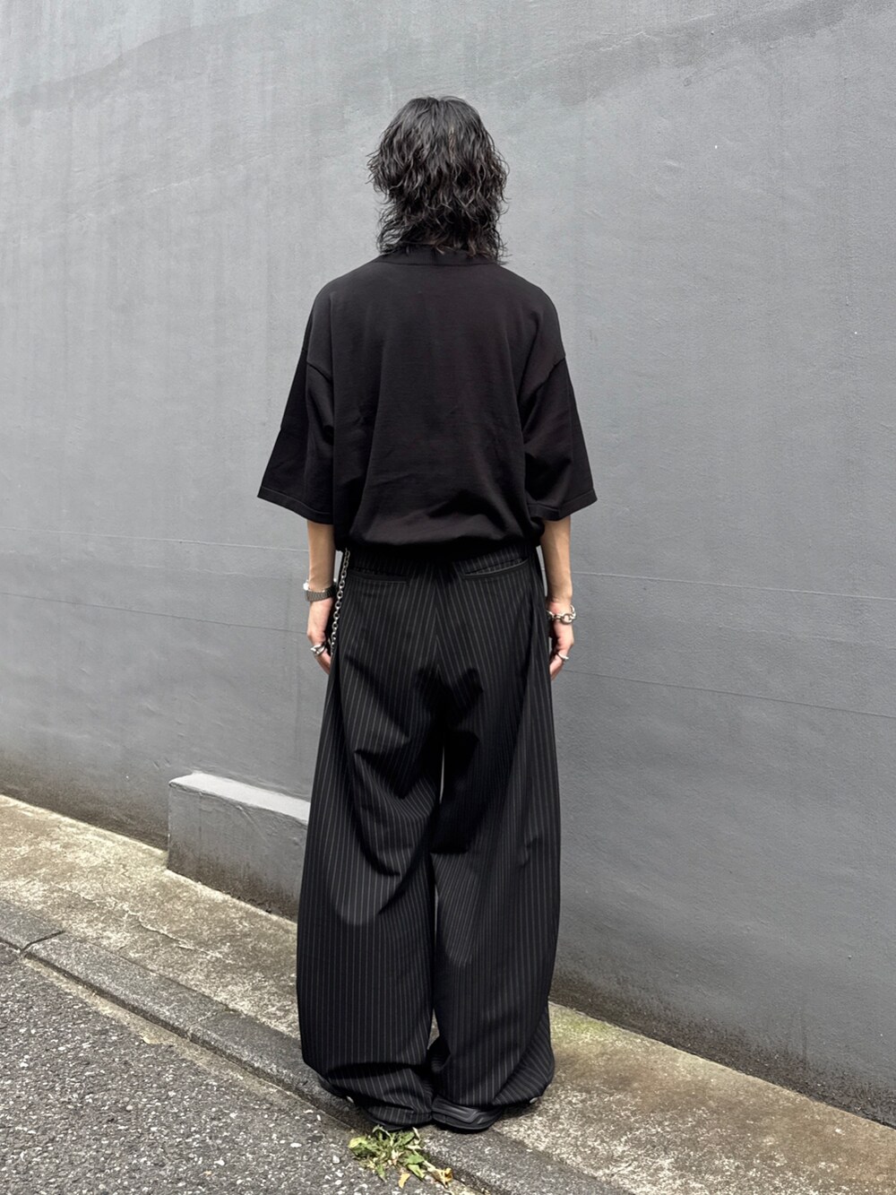 ブラック系のTシャツ/カットソー、ブラック系のスラックス、シルバー系のウォレットチェーンを着用したメンズの夏コーディネートの3枚目の写真