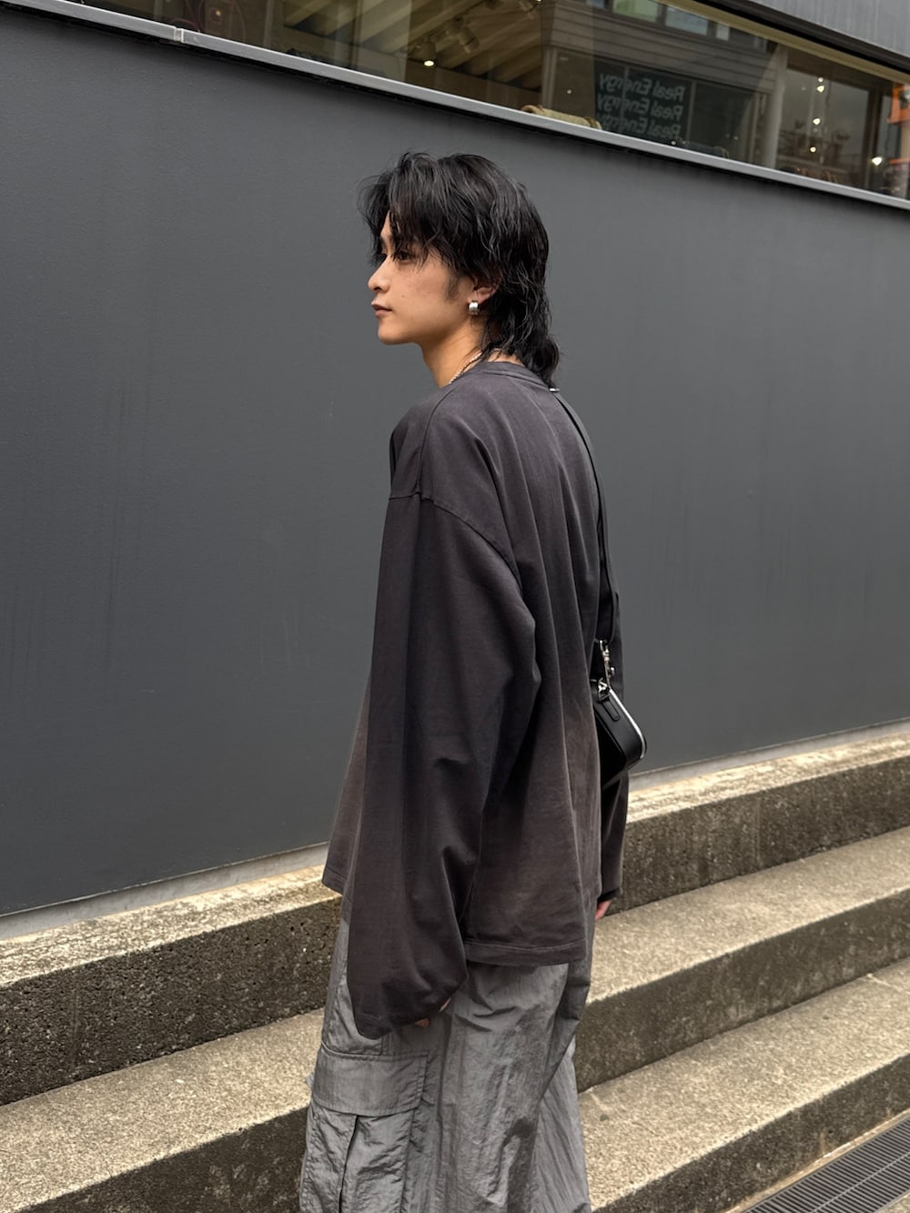 ブラック系のTシャツ/カットソー、グレー系のカーゴパンツ、ブラック系のショルダーバッグを着用したメンズの春コーディネートの5枚目の写真