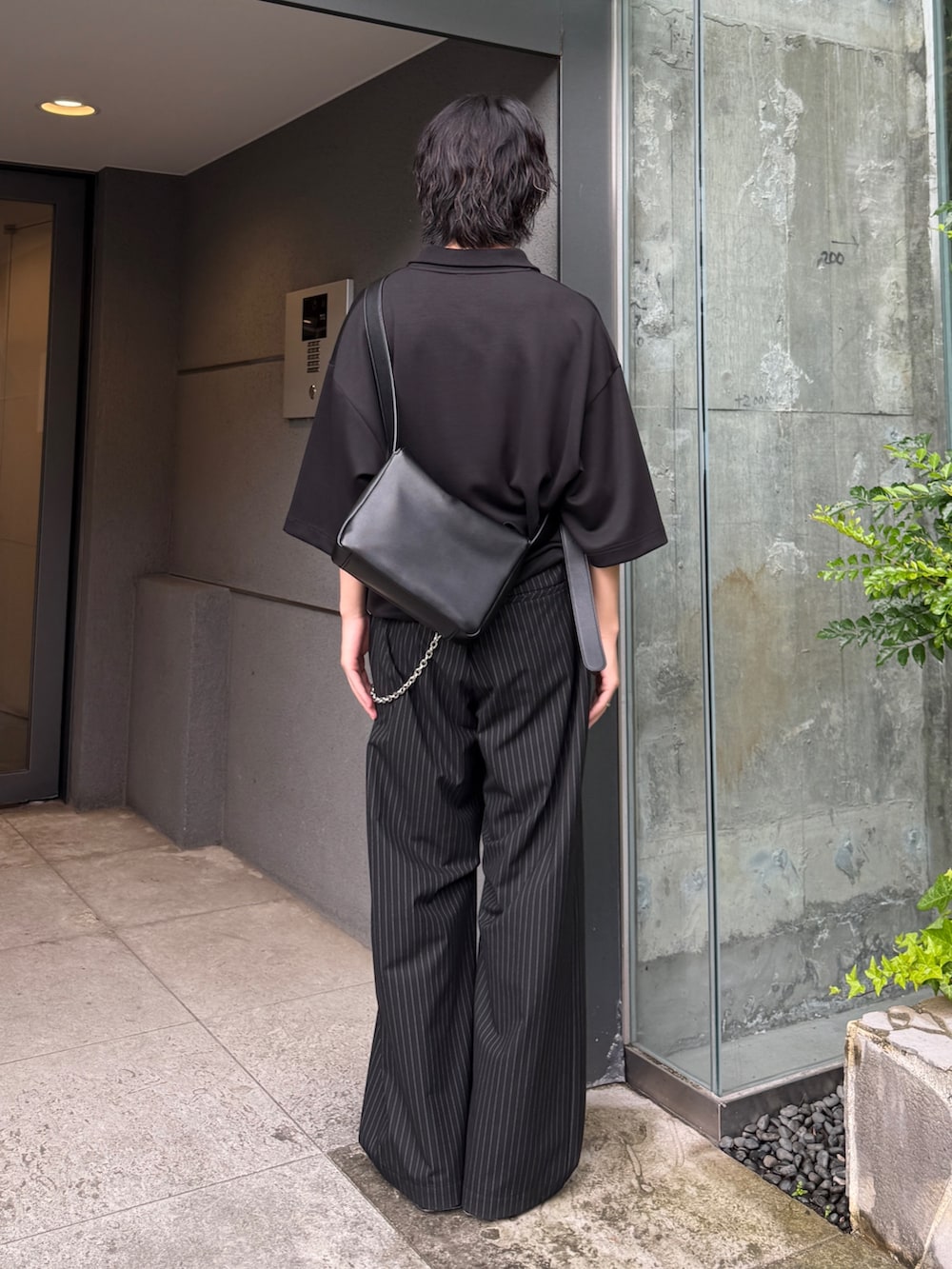 ブラック系のスラックス、ブラック系のTシャツ/カットソー、ブラック系のショルダーバッグを着用したメンズの夏コーディネートの4枚目の写真