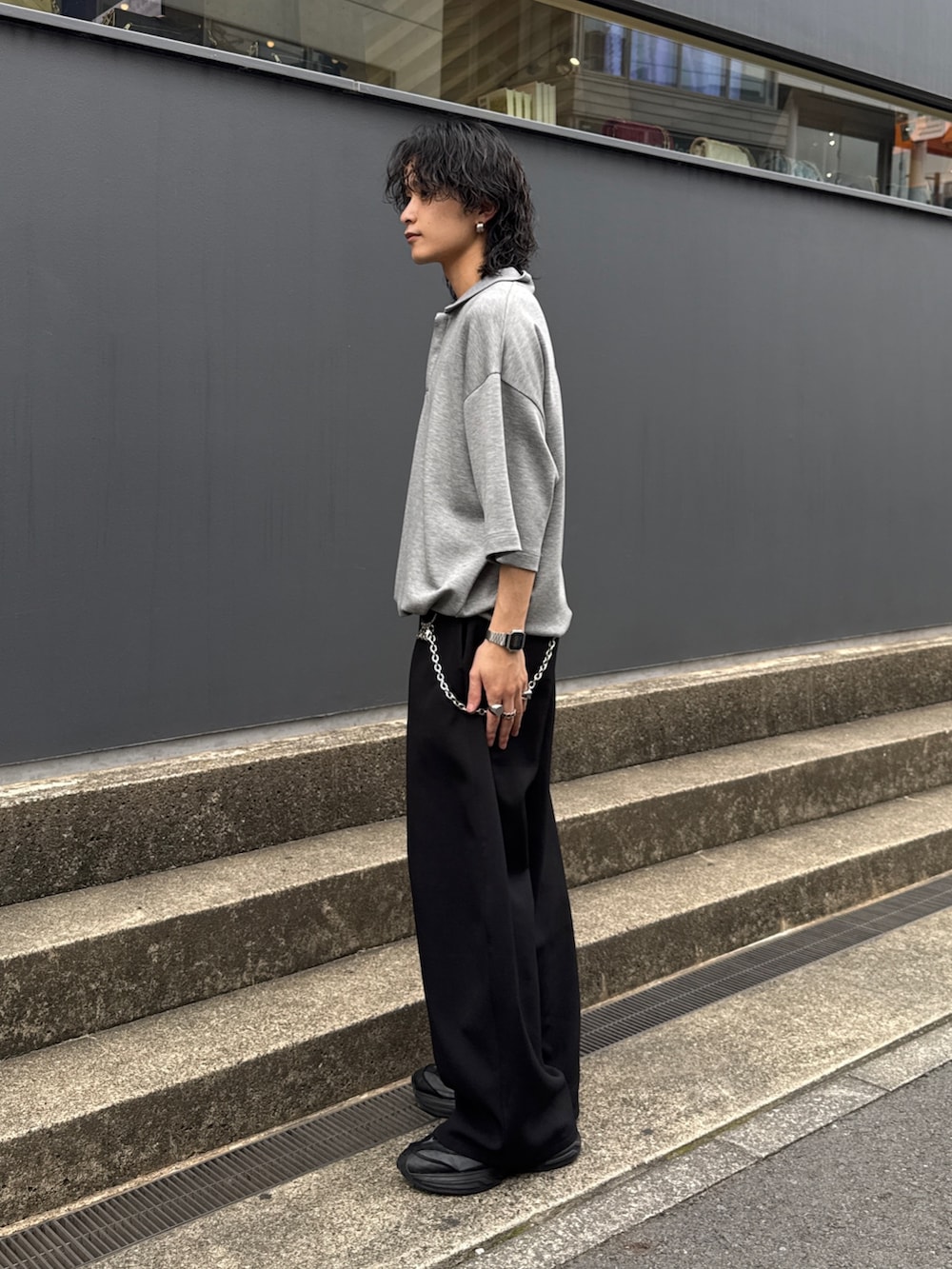 グレー系のTシャツ/カットソー、ブラック系のスラックス、シルバー系のウォレットチェーンを着用したメンズの夏コーディネートの2枚目の写真