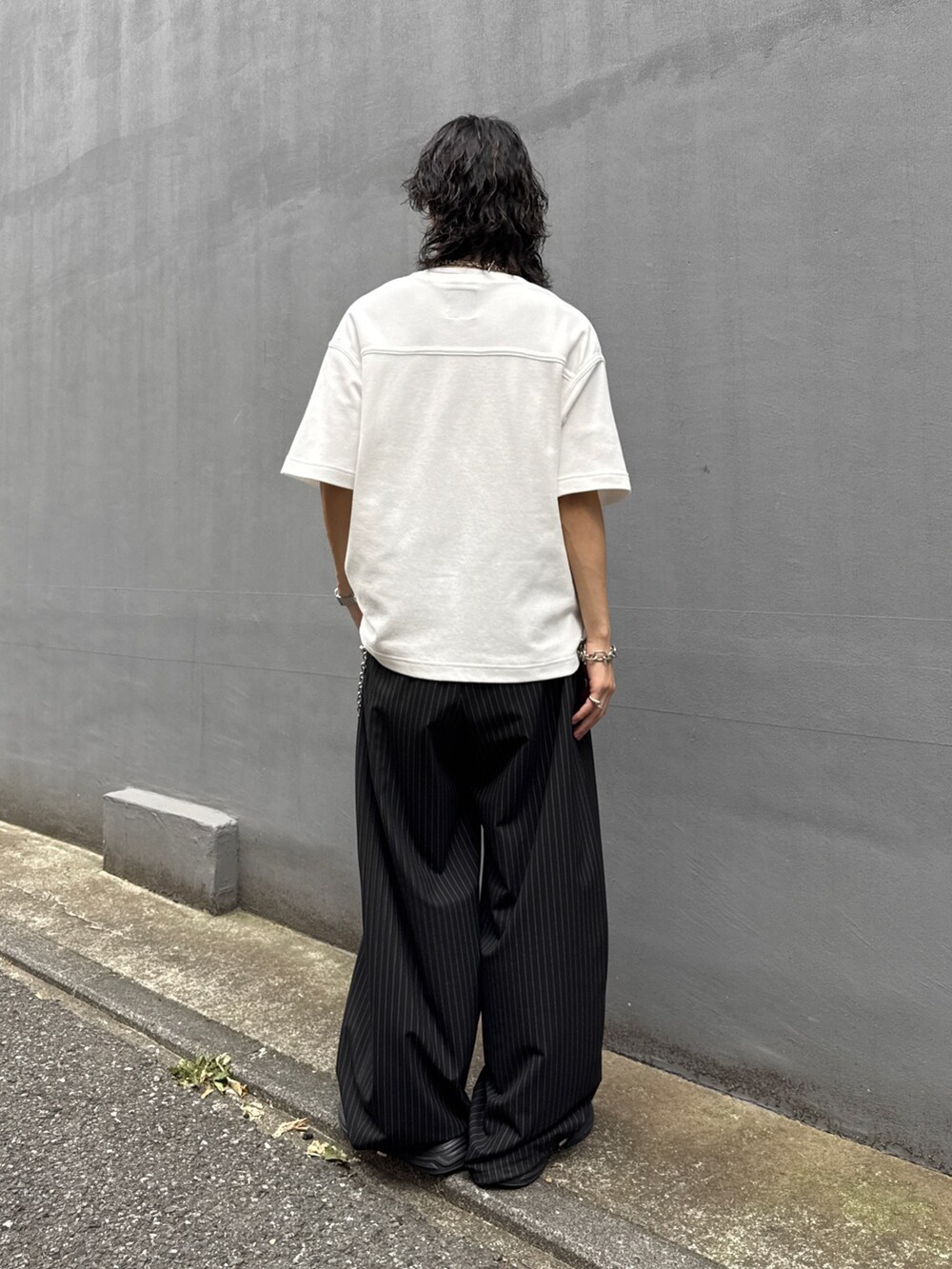 ホワイト系のTシャツ/カットソー、ブラック系のスラックス、シルバー系のウォレットチェーンを着用したメンズの夏コーディネートの3枚目の写真