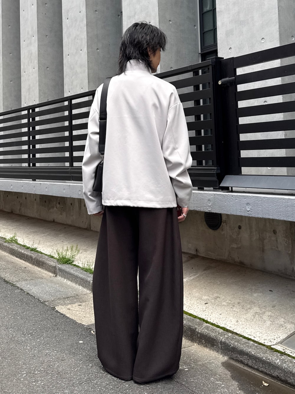 グレー系のスラックス、グレー系のブルゾン、ブラック系のショルダーバッグを着用したメンズの春コーディネートの3枚目の写真