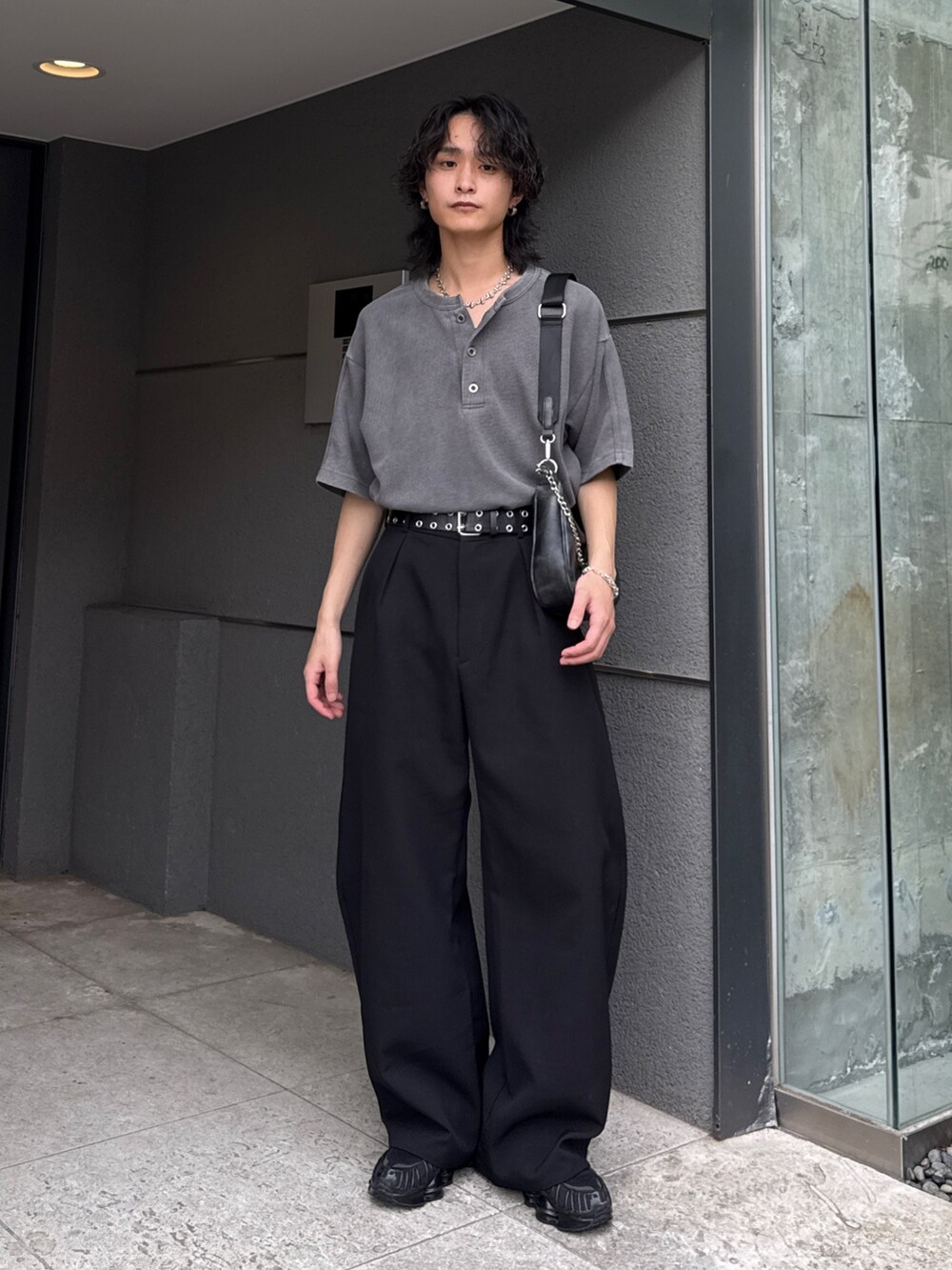 グレー系のTシャツ/カットソー、ブラック系のショルダーバッグ、ブラック系のスラックスを着用したメンズの春コーディネートの2枚目の写真