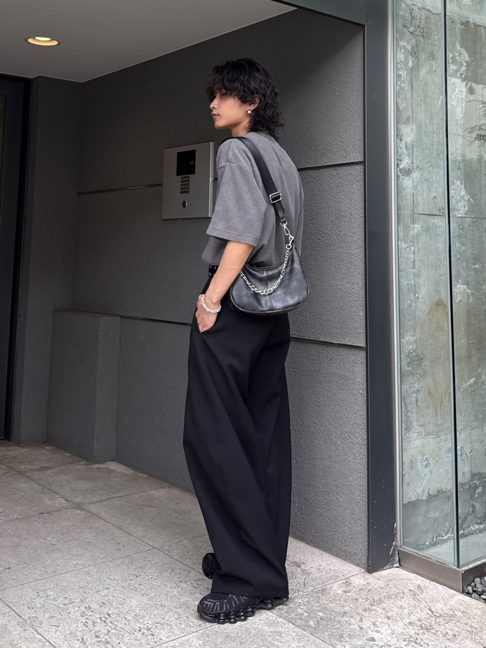 グレー系のTシャツ/カットソー、ブラック系のショルダーバッグ、ブラック系のスラックスを着用したメンズの春コーディネートの3枚目の写真