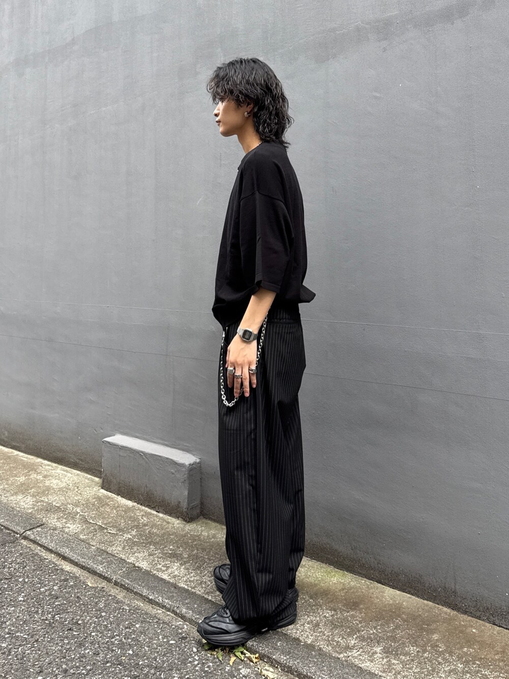 ブラック系のTシャツ/カットソー、ブラック系のスラックス、シルバー系のウォレットチェーンを着用したメンズの夏コーディネートの2枚目の写真