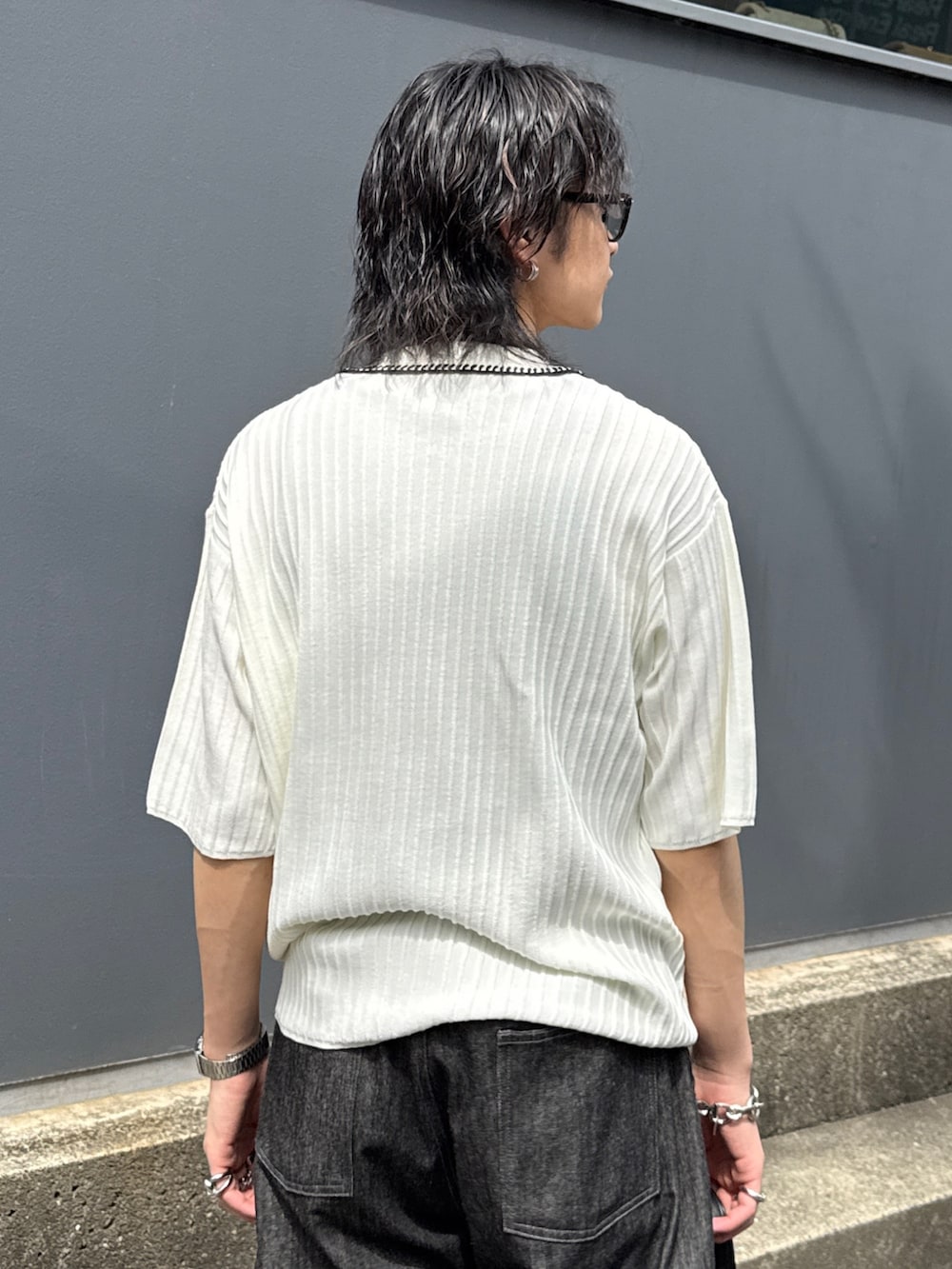 ブラック系のデニムパンツ、ブラック系のショルダーバッグ、ホワイト系のニット/セーターを着用したメンズの春コーディネートの6枚目の写真