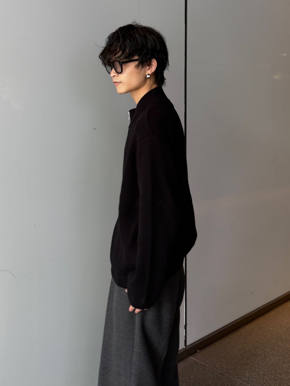 ブラック系のニット/セーター、グレー系のスラックスを着用したメンズの秋コーディネートの5枚目の写真