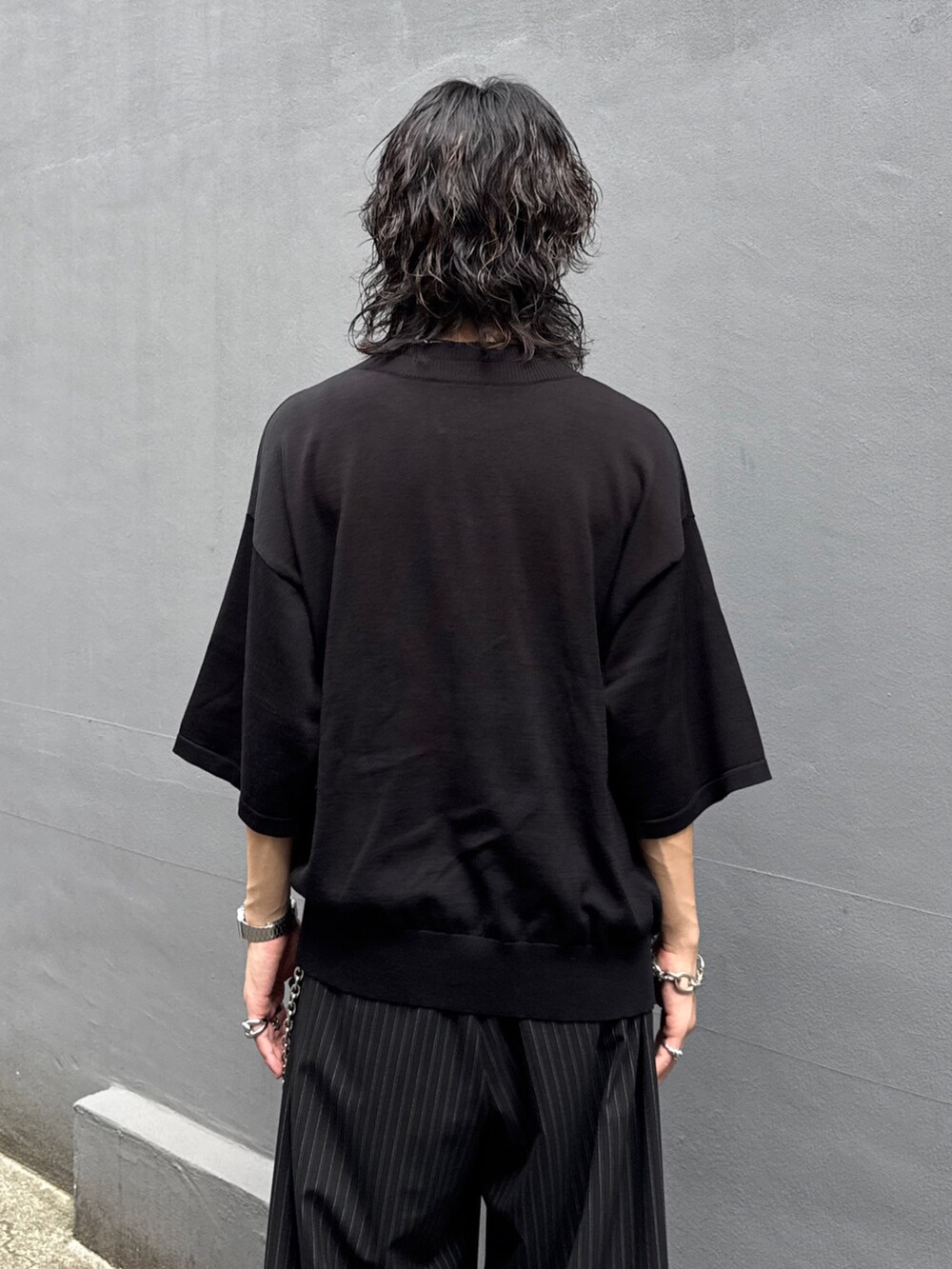 ブラック系のTシャツ/カットソー、ブラック系のスラックス、シルバー系のウォレットチェーンを着用したメンズの夏コーディネートの6枚目の写真