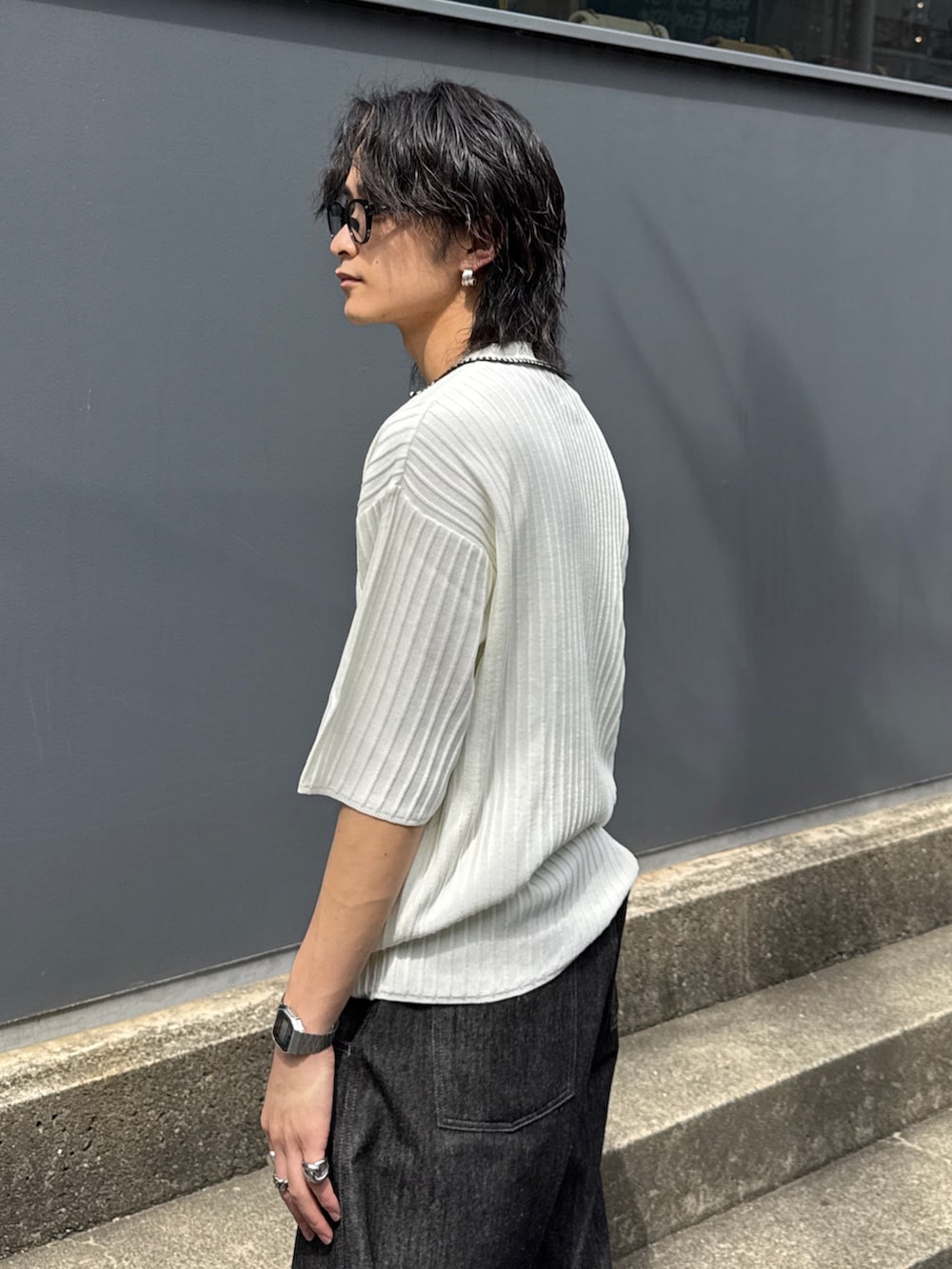 ブラック系のデニムパンツ、ブラック系のショルダーバッグ、ホワイト系のニット/セーターを着用したメンズの春コーディネートの5枚目の写真