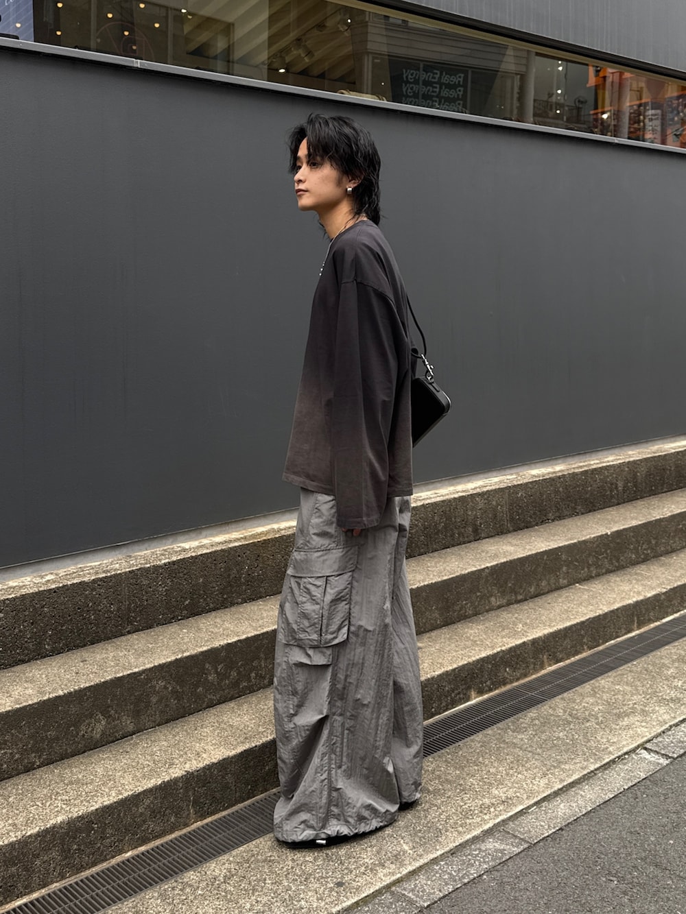 ブラック系のTシャツ/カットソー、グレー系のカーゴパンツ、ブラック系のショルダーバッグを着用したメンズの春コーディネートの2枚目の写真