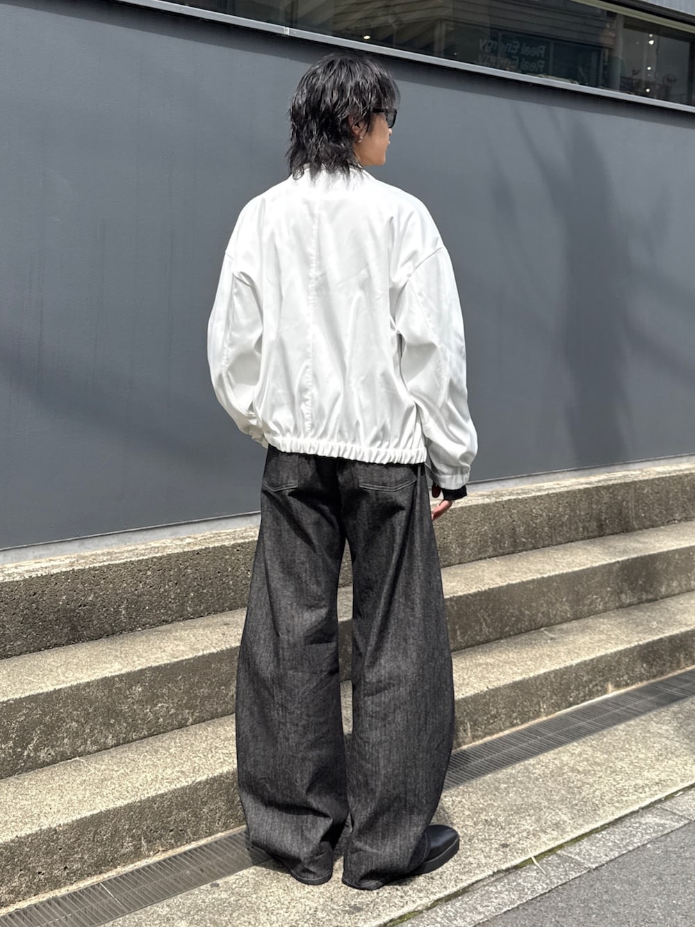 ホワイト系のブルゾン、ブラック系のTシャツ/カットソー、ブラック系のデニムパンツを着用したメンズの春コーディネートの3枚目の写真