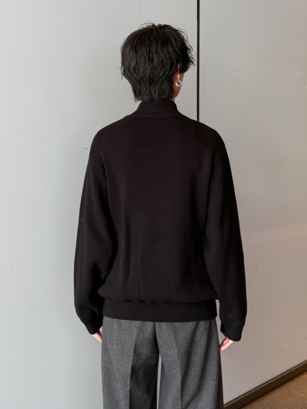ブラック系のニット/セーター、グレー系のスラックスを着用したメンズの秋コーディネートの6枚目の写真