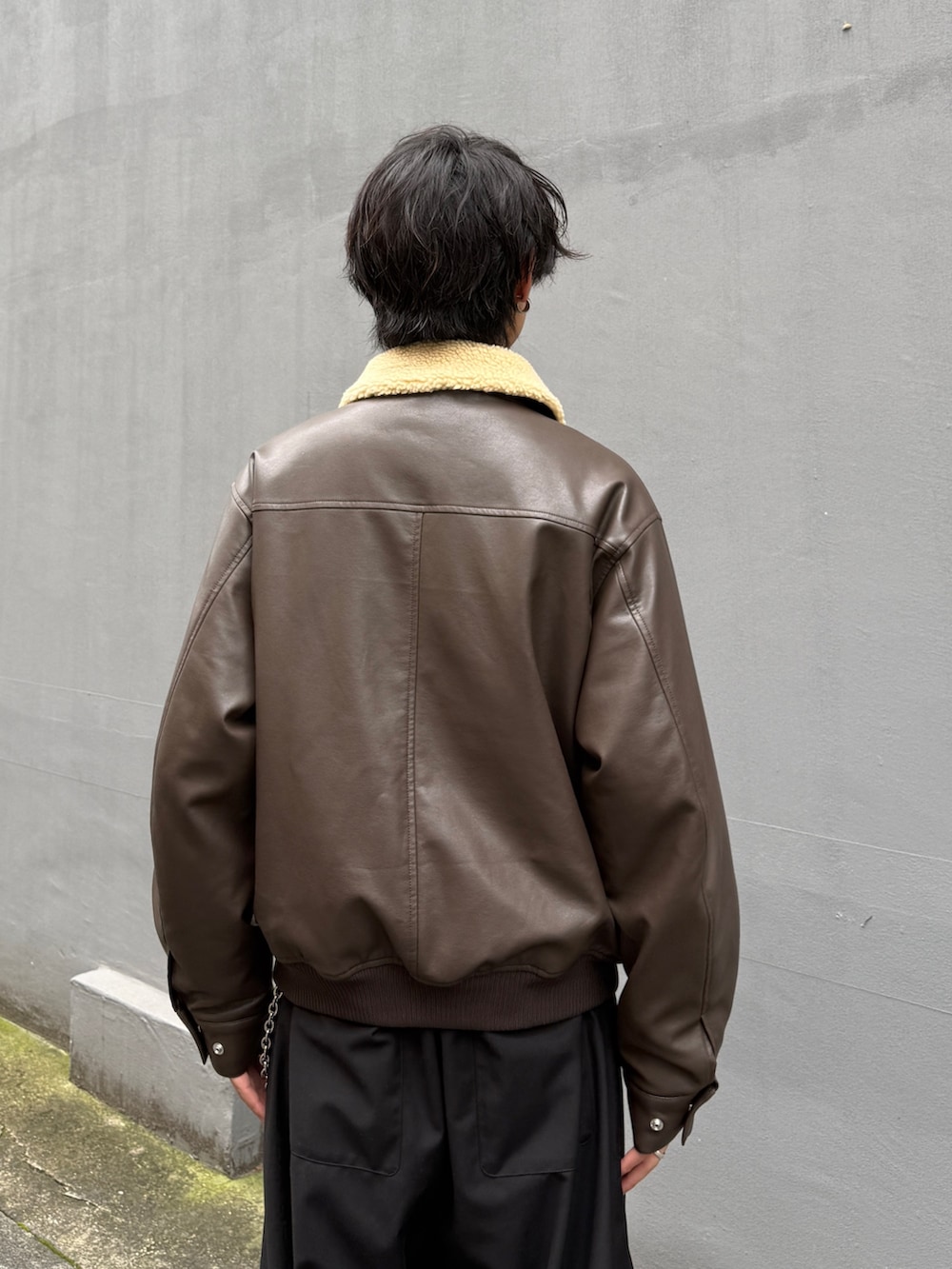 ブラック系のニット/セーター、ブラウン系のブルゾン、ブラック系のスラックスを着用したメンズの秋コーディネートの5枚目の写真