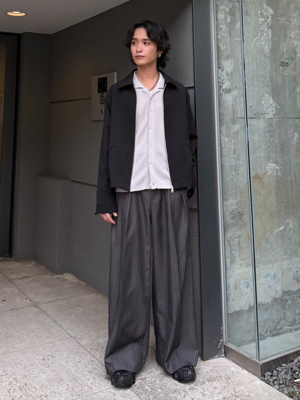 グレー系のスラックス、グレー系のシャツ/ブラウス、ブラック系のブルゾンを着用したメンズの夏コーディネートの2枚目の写真