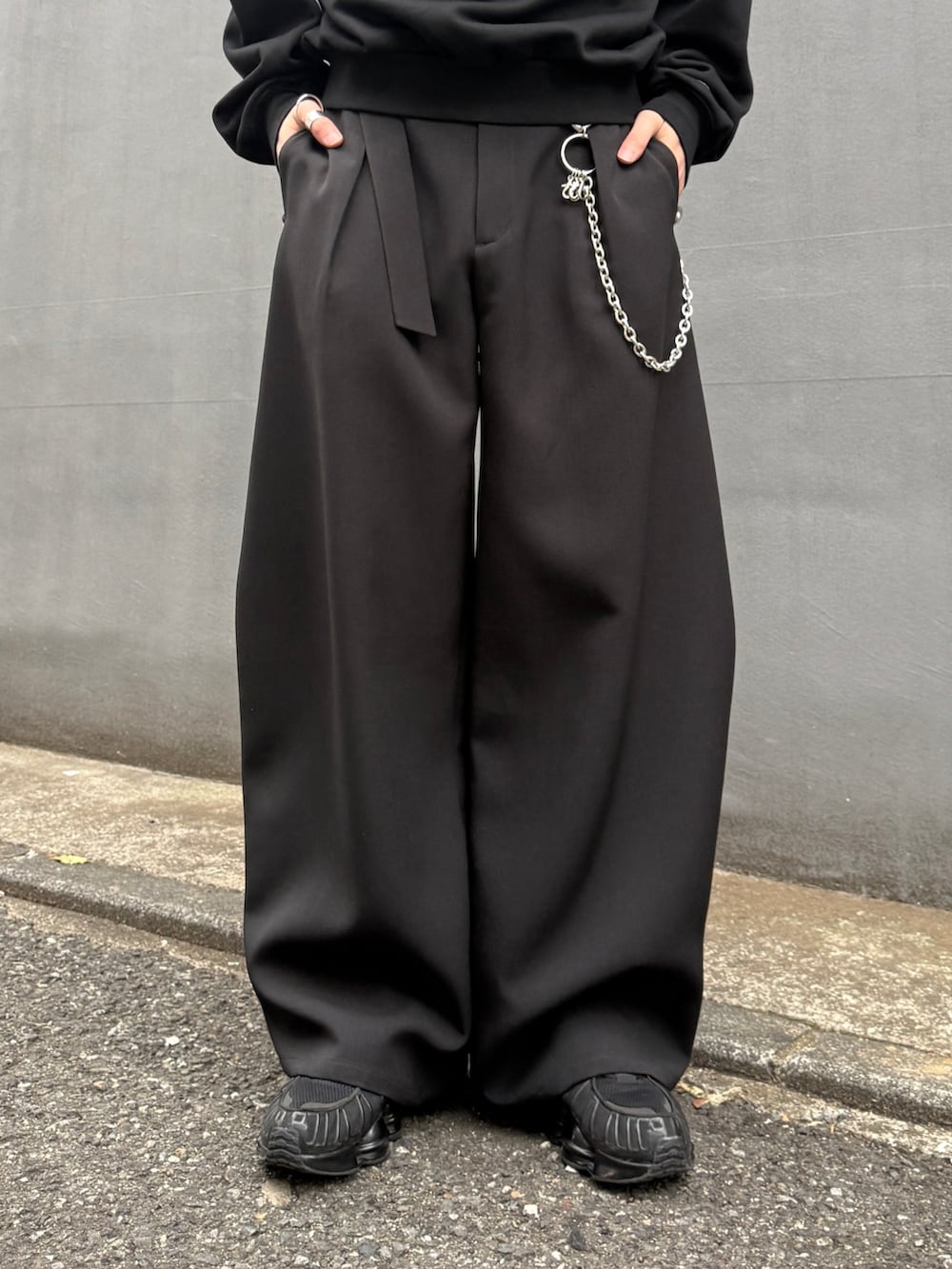 ブラック系のスウェット、ブラック系のスラックス、シルバー系のウォレットチェーンを着用したメンズの春コーディネートの7枚目の写真