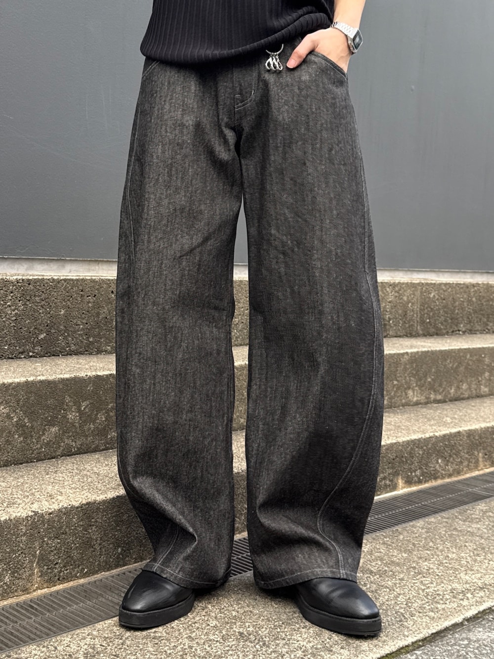 ブラック系のニット/セーター、ブラック系のショルダーバッグ、ブラック系のデニムパンツを着用したメンズの春コーディネートの7枚目の写真