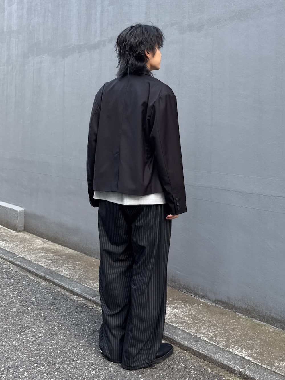 ブラック系のテーラードジャケット、グレー系のシャツ/ブラウス、ブラック系のスラックスを着用したメンズの春コーディネートの3枚目の写真