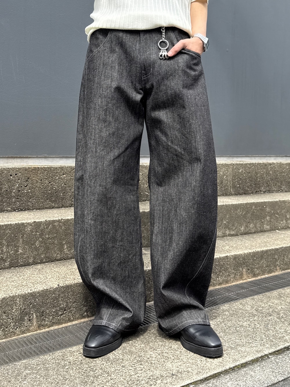 ブラック系のデニムパンツ、ブラック系のショルダーバッグ、ホワイト系のニット/セーターを着用したメンズの春コーディネートの9枚目の写真