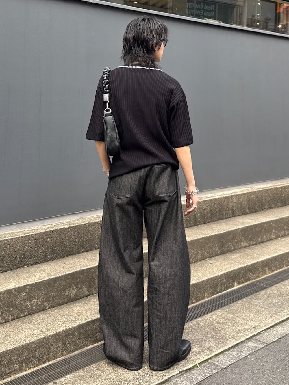 ブラック系のニット/セーター、ブラック系のショルダーバッグ、ブラック系のデニムパンツを着用したメンズの春コーディネートの3枚目の写真