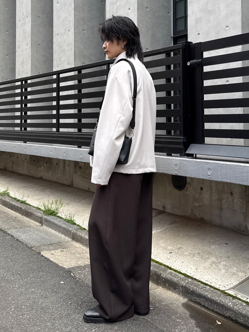 グレー系のスラックス、グレー系のブルゾン、ブラック系のショルダーバッグを着用したメンズの春コーディネートの2枚目の写真
