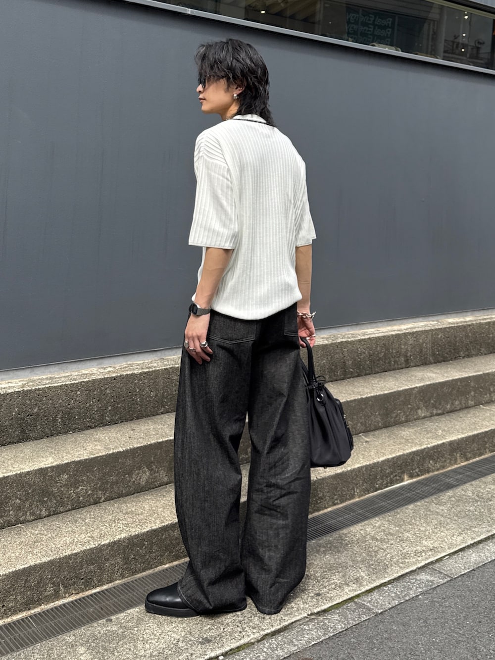 ブラック系のデニムパンツ、ブラック系のショルダーバッグ、ホワイト系のニット/セーターを着用したメンズの春コーディネートの8枚目の写真
