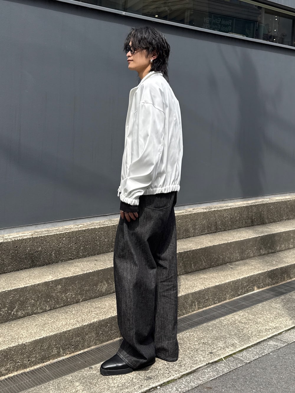 ホワイト系のブルゾン、ブラック系のTシャツ/カットソー、ブラック系のデニムパンツを着用したメンズの春コーディネートの2枚目の写真