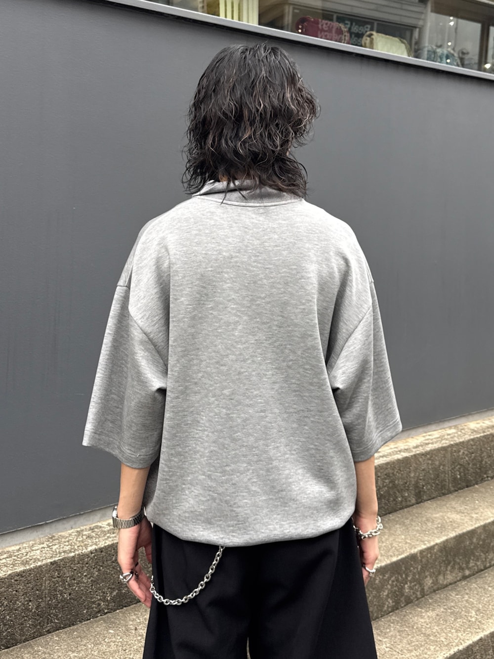 グレー系のTシャツ/カットソー、ブラック系のスラックス、シルバー系のウォレットチェーンを着用したメンズの夏コーディネートの6枚目の写真