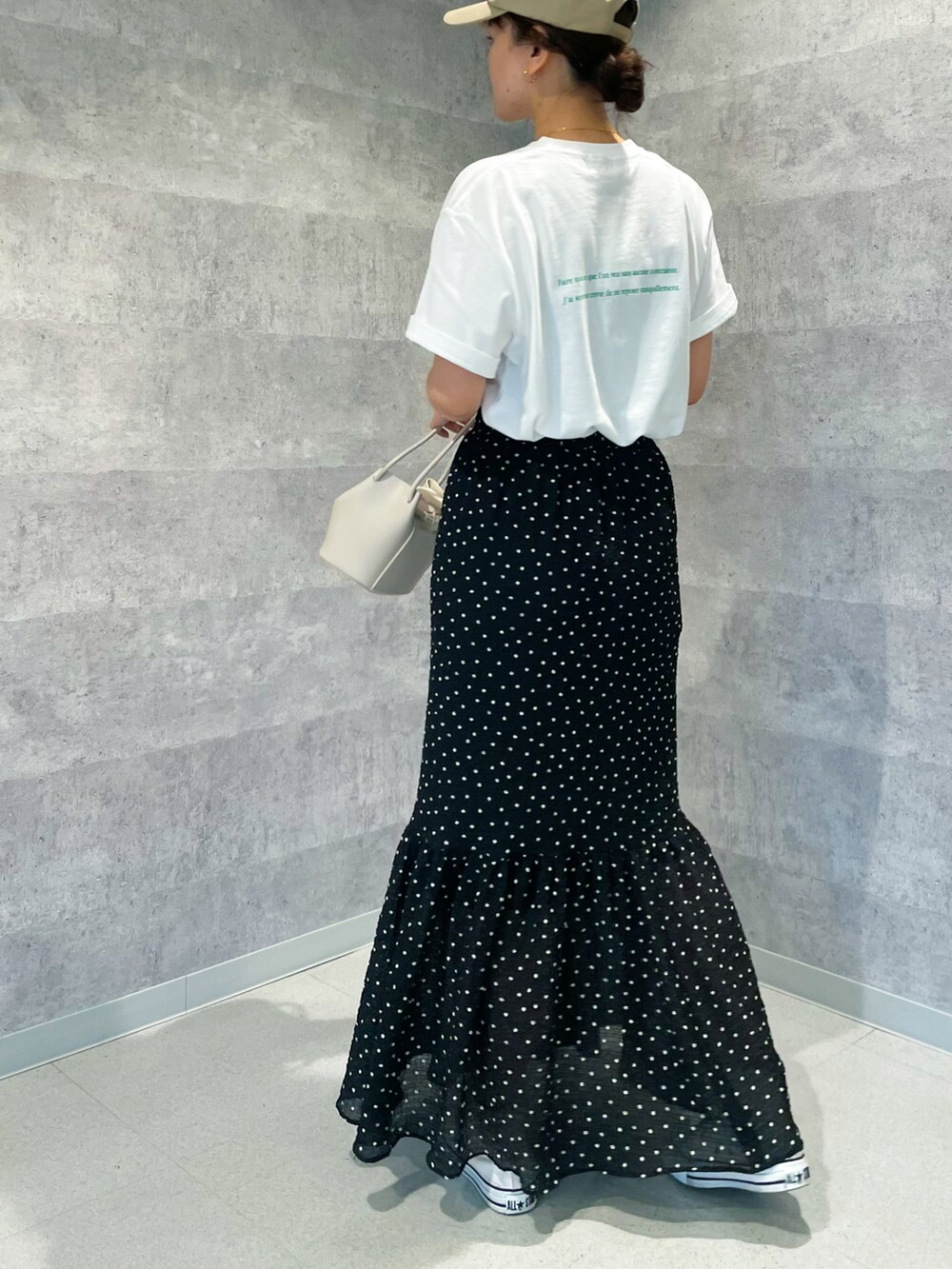 グリーン系のTシャツ/カットソー、ブラック系のスカート、ベージュ系のショルダーバッグを着用したレディースの春コーディネートの5枚目の写真