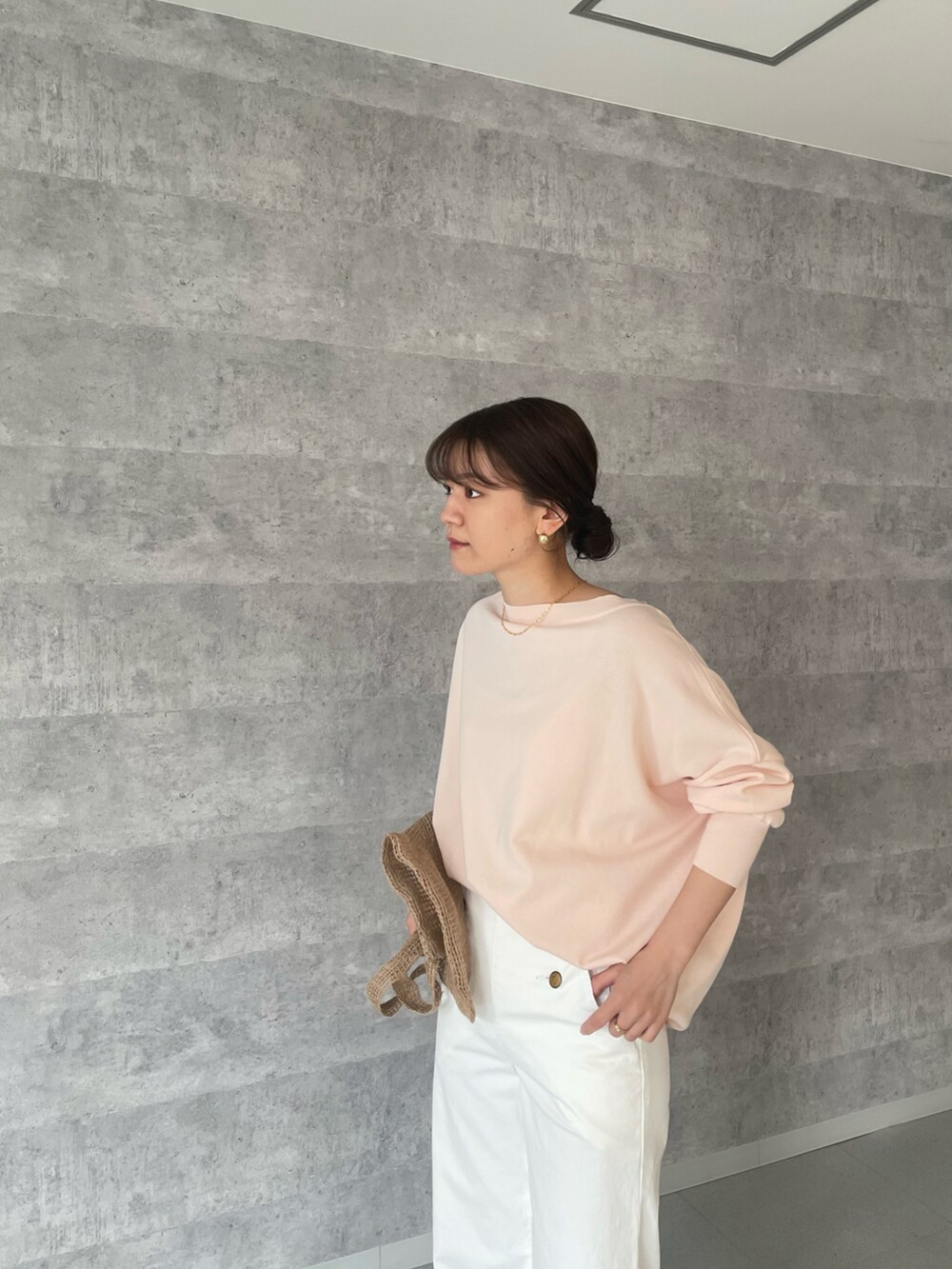 ピンク系のニット/セーター、ホワイト系のデニムパンツ、ベージュ系のバッグを着用したレディースの春コーディネートの2枚目の写真