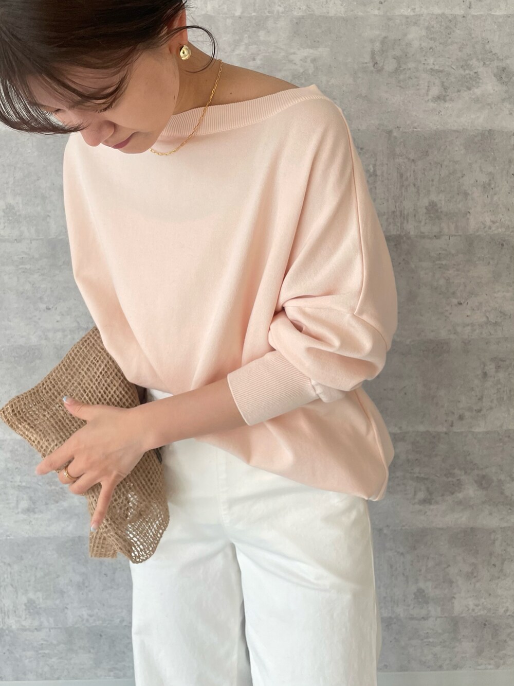 ピンク系のニット/セーター、ホワイト系のデニムパンツ、ベージュ系のバッグを着用したレディースの春コーディネートの3枚目の写真