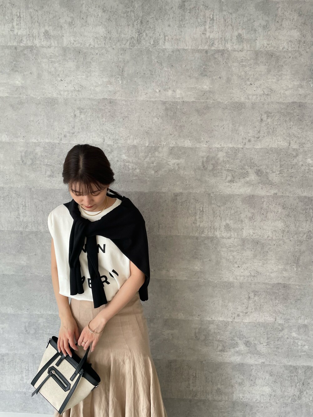 ホワイト系のTシャツ/カットソー、ブラック系のカーディガン/ボレロ、ベージュ系のスカートを着用したレディースの春コーディネートの2枚目の写真