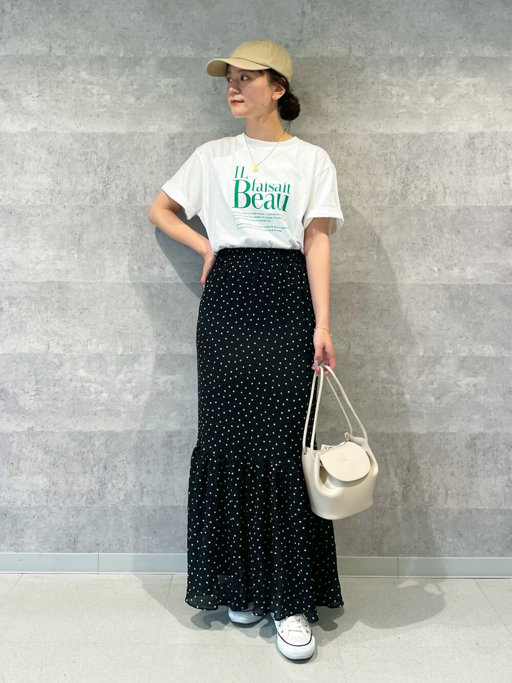 グリーン系のTシャツ/カットソー、ブラック系のスカート、ベージュ系のショルダーバッグを着用したレディースの春コーディネートの2枚目の写真