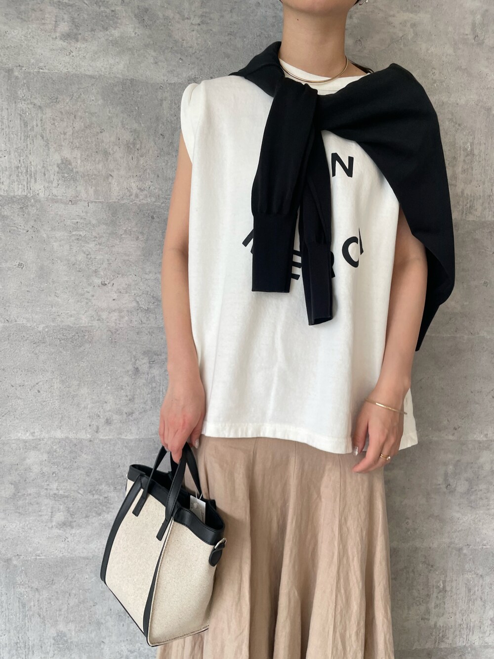 ホワイト系のTシャツ/カットソー、ブラック系のカーディガン/ボレロ、ベージュ系のスカートを着用したレディースの春コーディネートの3枚目の写真