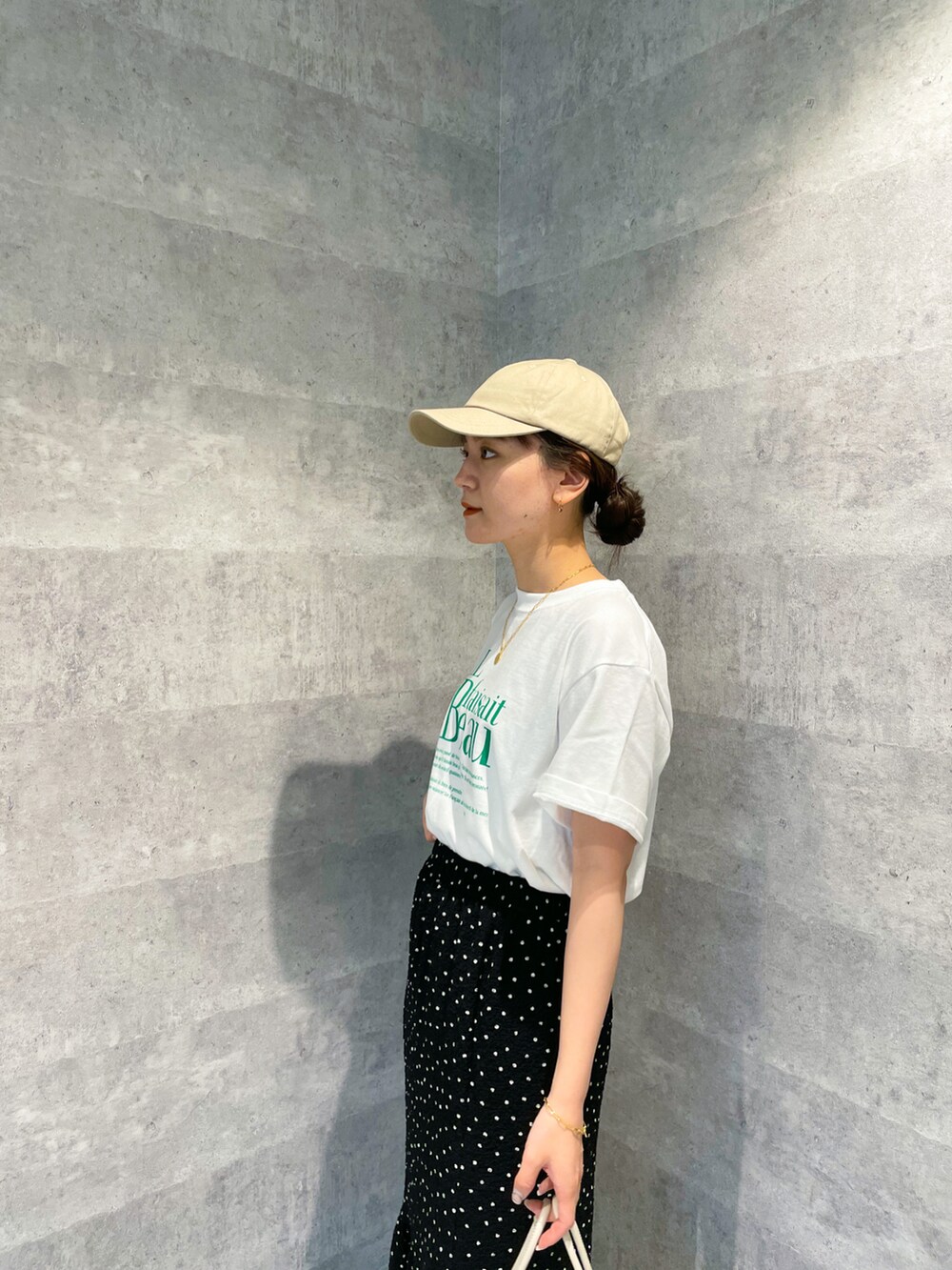 グリーン系のTシャツ/カットソー、ブラック系のスカート、ベージュ系のショルダーバッグを着用したレディースの春コーディネートの3枚目の写真