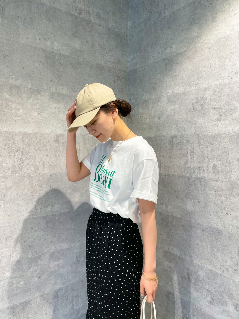 グリーン系のTシャツ/カットソー、ブラック系のスカート、ベージュ系のショルダーバッグを着用したレディースの春コーディネートの4枚目の写真