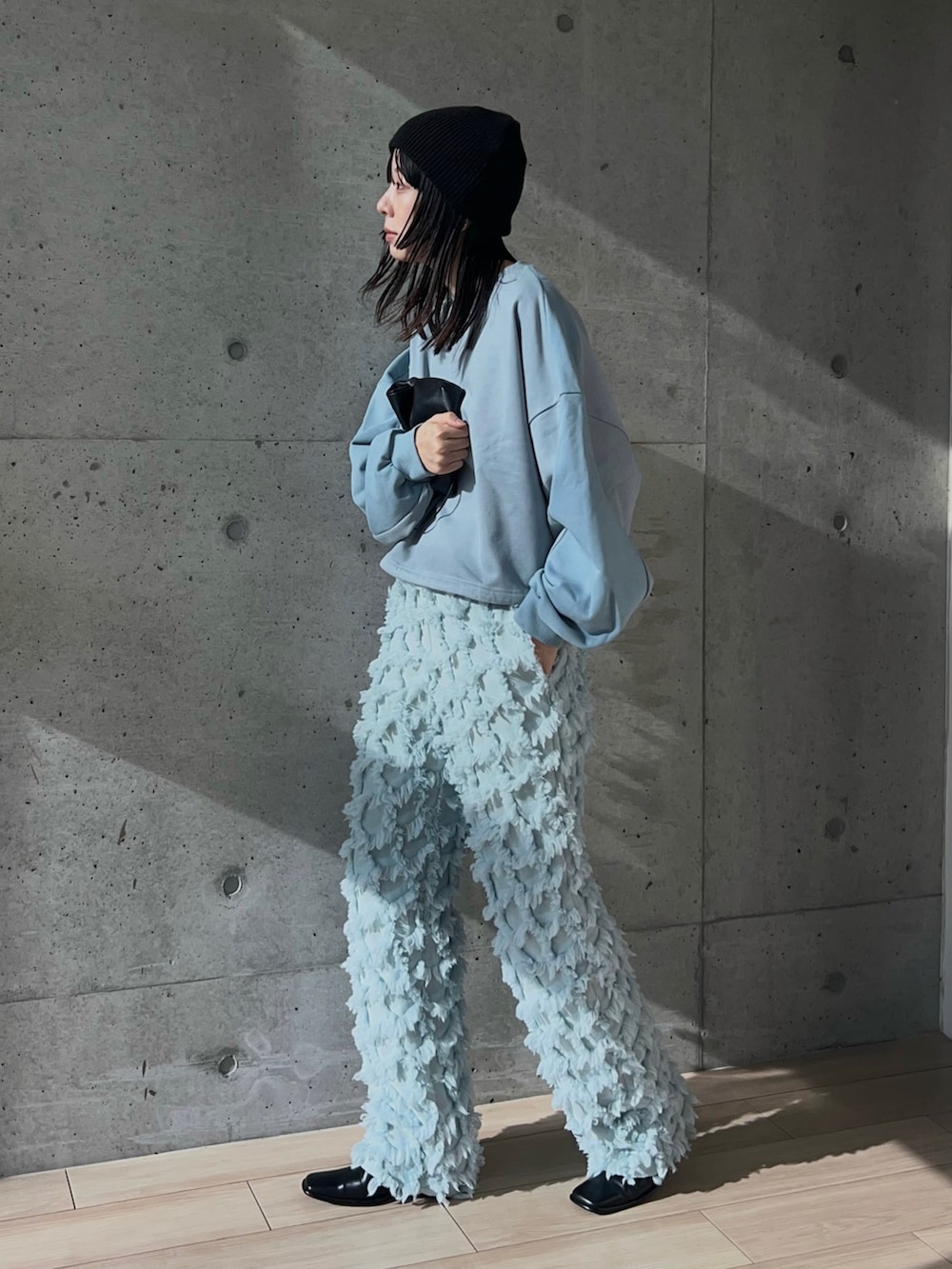 ブルー系のスウェット、ブルー系のパンツ、ブラック系のショルダーバッグを着用したレディースの秋コーディネートの4枚目の写真